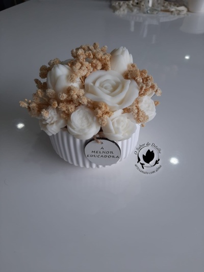 Arranjo decorativo com flores brancas artificiais e ramos secos em base branca com etiqueta