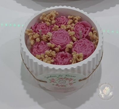 Vela decorativa em recipiente branco com flores rosas em cera e corda de juta