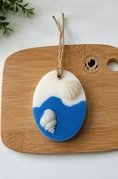 Ornamento oval branco e azul com conchas e cordão sobre tábua de madeira