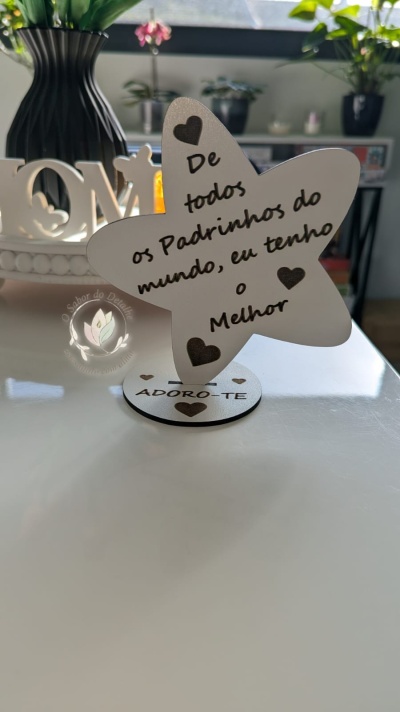 Suporte decorativo em forma de estrela com texto para padrinhos sobre mesa branca