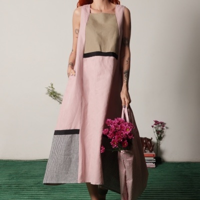 Vestido comprido rosa e bege com padrão xadrez, mulher ruiva com saco e flores