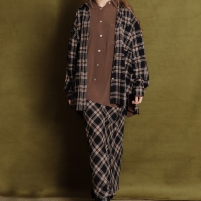 Conjunto de roupa xadrez castanho com camisa castanha e botins pretos sobre fundo verde