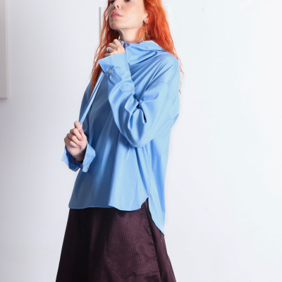 Blusa azul de tecido liso com gola alta e saia castanha longa com bolso