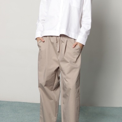 Pessoa a usar camisa branca, calças bege largas, lenço colorido e sapatos pretos