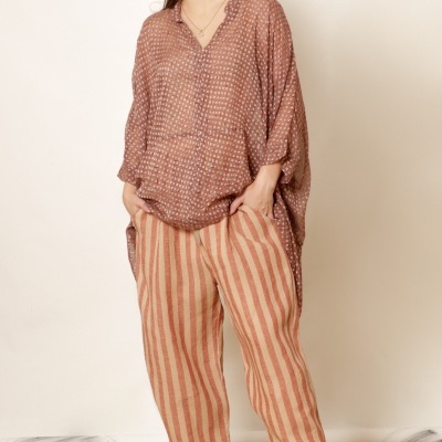 Mulher vestindo blusa castanha estampada e calças largas riscas bege e castanho com sapatos castanhos