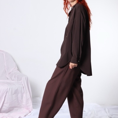 Pessoa com camisa oversized castanha, calças largas castanhas e sandálias pretas