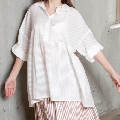 Mulher a usar blusa branca riscada com saia comprida riscada e ambiente rústico