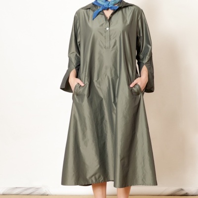 Modelo com vestido midi verde-oliva de tecido acetinado, lenço azul no pescoço e sandálias verdes.