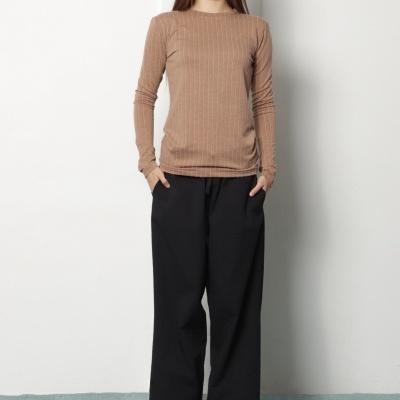 Mulher com camisola castanha riscada e calças pretas largas