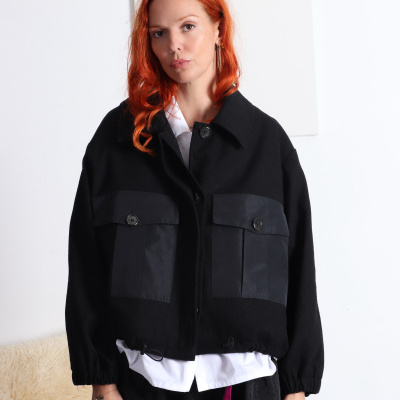 Mulher com casaco preto e cabelo ruivo, fundo branco.