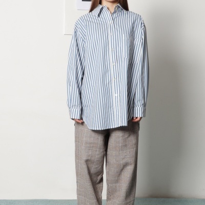 Mulher com camisa listrada azul e branca e calças xadrez castanho-bege com sapatilhas brancas