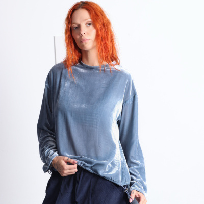 Mulher com blusa cinza de veludo e calças azuis escuras