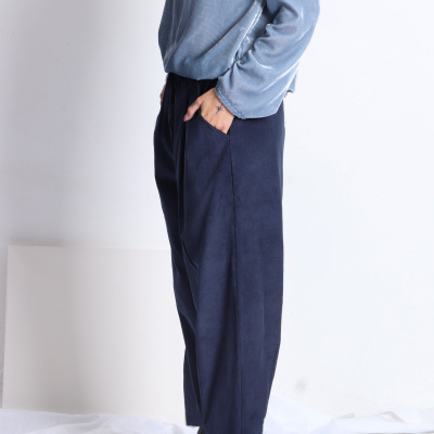Calças largas azul escuro, camisola azul clara aveludada e sapatos pretos em fundo branco.