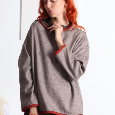 Camisola cinza castanha com bordas em laranja usada por mulher ruiva.