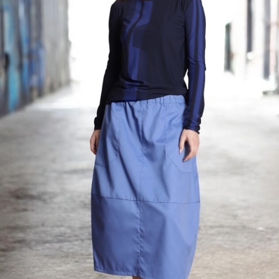 Mulher veste camiseta azul escuro com padrão azul, saia azul clara e sandálias azuis