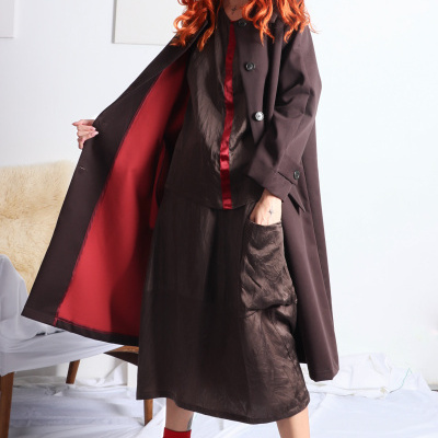 Mulher ruiva com casaco castanho e interior vermelho em fundo branco