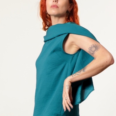 Mulher com blusa azul turquesa sem mangas e calças castanhas