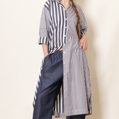 Mulher com vestido comprido às riscas azul e branco e calças largas azuis