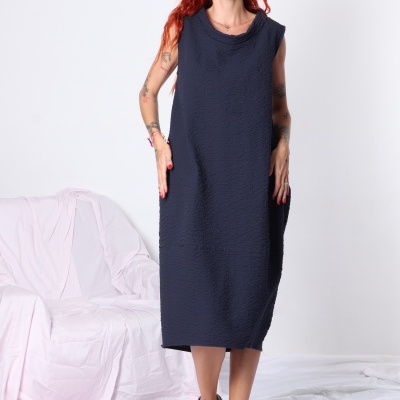 Vestido midi azul escuro texturizado sem mangas em modelo com sandálias verdes em cenário branco.