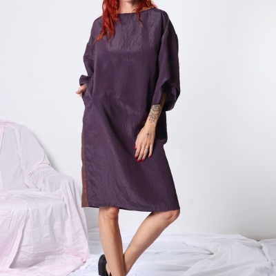 Vestido roxo escuro ligeiramente brilhante com sandálias pretas, mulher ruiva com cabelo ondulado em fundo branco.