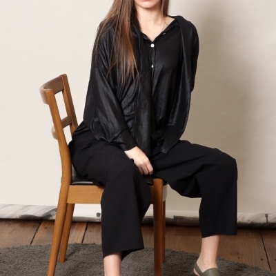 Mulher sentada com roupa preta e sandálias verdes num tapete cinza