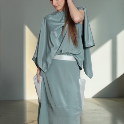 Conjunto feminino cinza-azulado acetinado com detalhes brancos, usado por modelo com cabelo liso castanho.