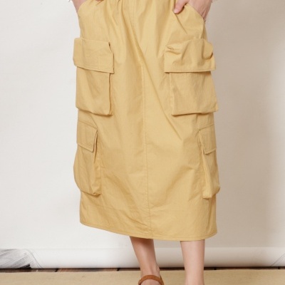 Saia midi bege com quatro bolsos grandes e blusa branca riscada