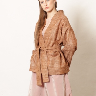Mulher com casaco castanho claro de malha e vestido rosa longo