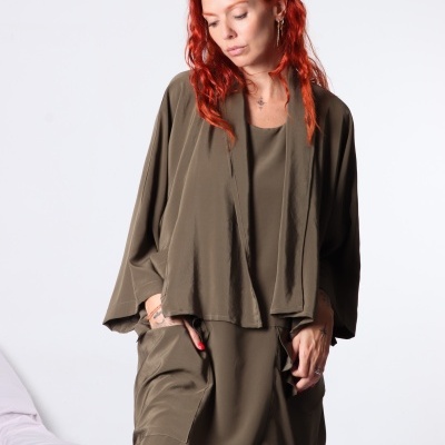 Mulher ruiva veste conjunto verde-oliva de casaco e calças largas contra fundo branco