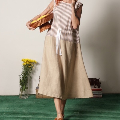 Mulher com vestido comprido bege e riscas a segurar cesto de limões com flores ao lado.