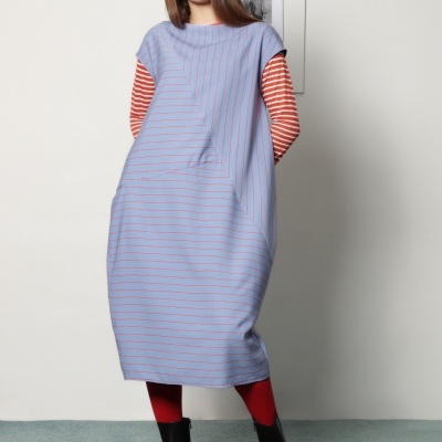 Mulher com vestido azul claro de riscas finas vermelhas e botas pretas