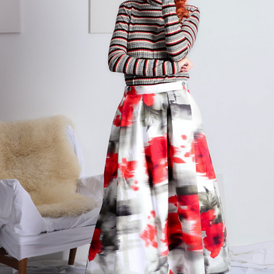 Mulher com camisola riscada e saia estampada em fundo branco com cadeira e pele sintética.