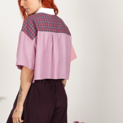 Camisa feminina rosa com padrão xadrez nas costas e gola branca, calças largas vinho e flores cor-de-rosa