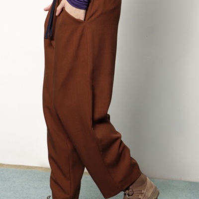 Calças castanhas largas com cordão preto e sapatilhas castanhas em ambiente interior
