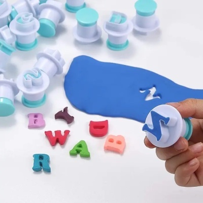 Carimbos de letras em plástico com argila azul e letras coloridas de argila no fundo