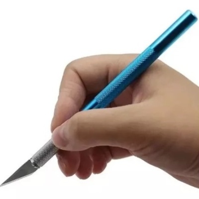 Mão segurando bisturi de precisão com cabo azul e lâmina prateada