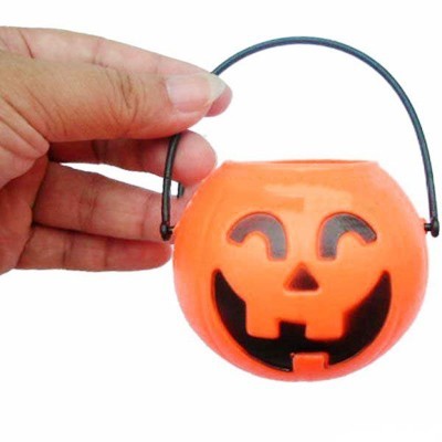 Mini balde de abóbora laranja com rosto sorridente preto e alça preta.