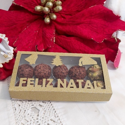 Caixa dourada com brigadeiros e a frase FELIZ NATAL em destaque