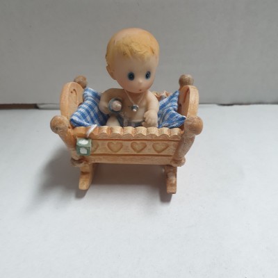 Boneco de bebé num berço de madeira com cobertor azul e branco