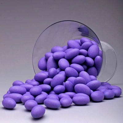 Copo de vidro tombado com amêndoas roxas espalhadas