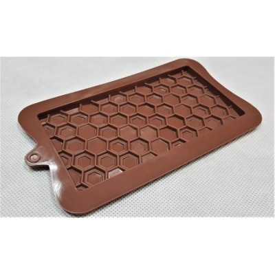 Forma de silicone castanha com padrão hexagonal colocado numa superfície branca