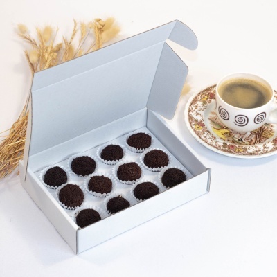 Caixa de brigadeiros com chávena de café e ramos de trigo ao fundo