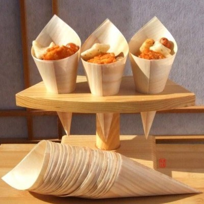 Três cones de madeira para snacks em suporte de madeira e pilha de cones idênticos ao lado