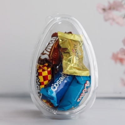Ovo de plástico transparente com chocolates embalados dentro
