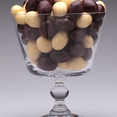 Taça de vidro com amendoins cobertos de chocolate castanhos e bege