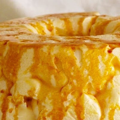 Bolo redondo cremoso coberto com calda amarelo-dourada