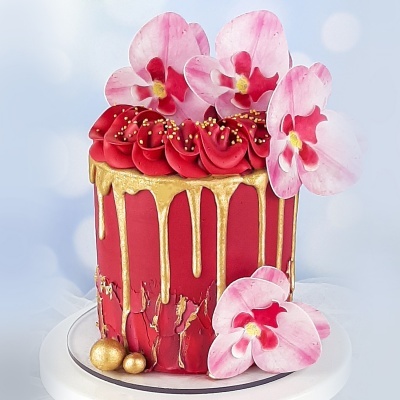 Bolo decorado em vermelho com gotas douradas e flores cor-de-rosa
