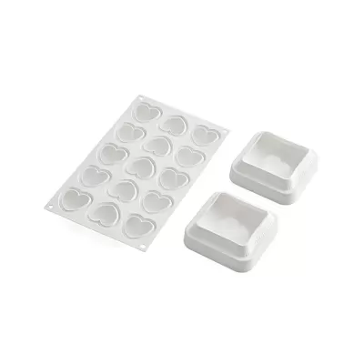 Formas de silicone branco para chocolate em forma de corações com duas espátulas brancas.