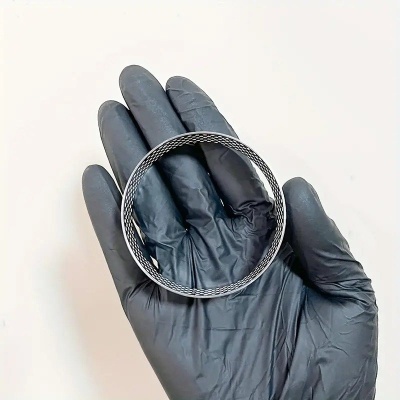 Pulseira rígida de metal com textura trançada segurada com luva preta