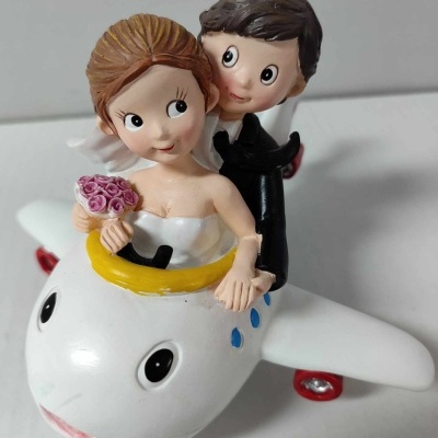 Bonecos de noivos em avião branco com detalhes coloridos